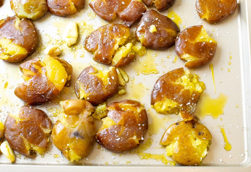 Potatoes smashed on a baking sheet before being baked.